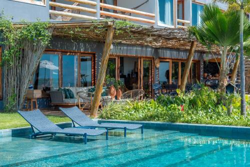 马拉戈日Villa Pantai Boutique Hotel Maragogi的一座带游泳池和椅子的度假村,毗邻一座房子