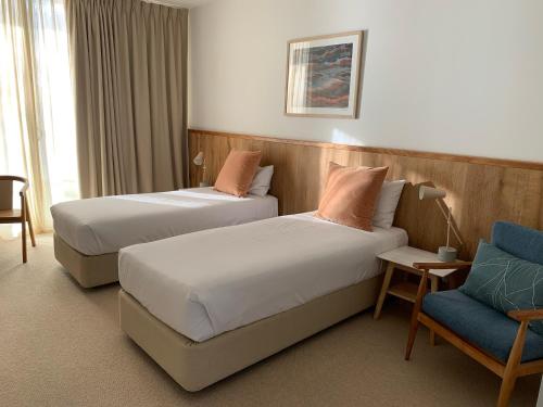 纳甘比尼冈比海滨汽车旅馆的酒店客房,配有两张床和椅子