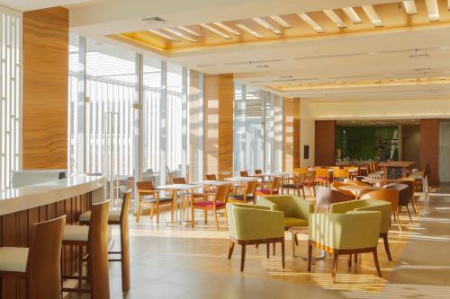 三宝垄三宝垄新邦利马快捷假日酒店的餐厅设有桌椅和窗户。