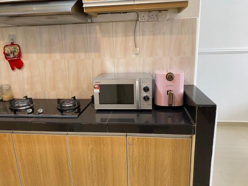 安邦Teratak Nenda的厨房配有微波炉,并在柜台上配有粉红色的电器