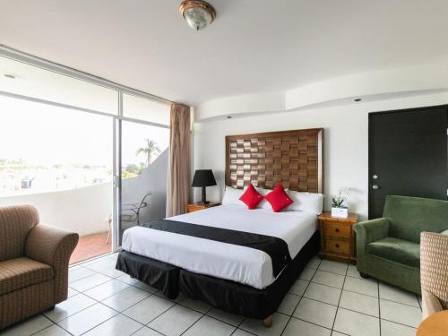 马萨特兰Zona Dorada Suites的酒店客房,配有一张床和两把椅子