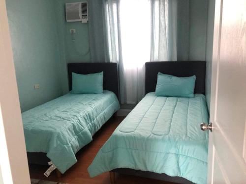 宿务Caza De Sierra-Home Staycation的一间卧室设有两张带蓝色床单的床和窗户。