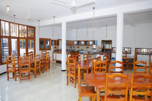 贾夫纳Amis Hotel & Restaurant的用餐室配有木桌和椅子