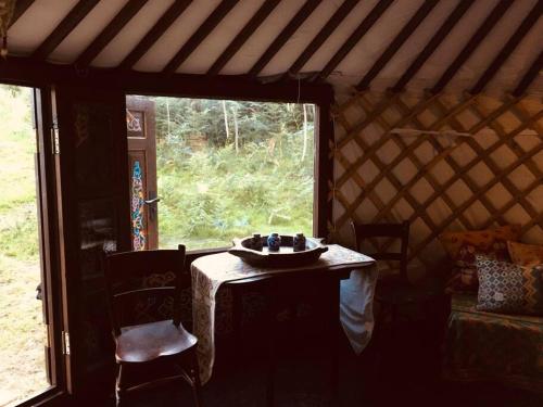 LlanbrynmairMongolian yurt sleeping 2+2 with outdoor space的圆顶帐篷内带桌子的房间,设有窗户