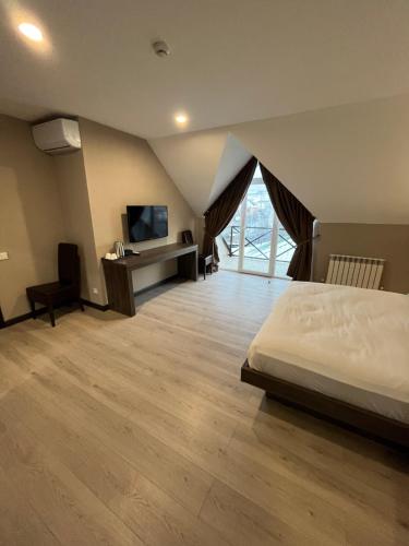 QaskelengResident Hotel Kaskelen的一间卧室配有一张床、一张书桌和一台电视