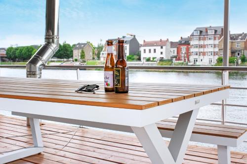 那慕尔Arcadia - Péniche de Standing à Namur avec vue sur la Citadelle的两瓶啤酒坐在码头的桌子上