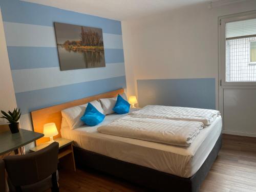 伍珀塔尔伍珀塔尔瑞斯德酒店的一间卧室配有一张带蓝色枕头的床和一张桌子
