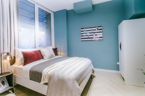 特拉维夫Monochrome Rothschild - Smart Hotel by Loginn Tel Aviv的一间卧室设有蓝色的墙壁和一张带窗户的床