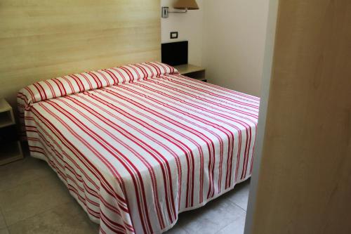 曼弗雷多尼亚Villaggio Baia Del Monaco的一张床上,床上有条纹毯子