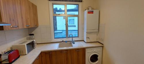 伦敦Family friendly 3 Bedroom Flat Zone 2 - children stay free!的厨房配有水槽、冰箱和窗户。