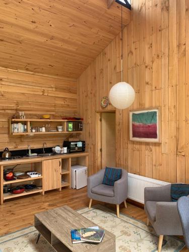 琼奇Cabaña Eco Loft Chiloe Chonchi的客厅设有木墙和桌椅