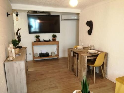 滨海自由城appartement cosy situé à 2mn de la plage à pied climatise的客厅配有桌子和墙上的电视