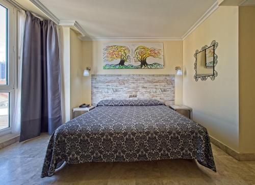 马德里游侠酒店的卧室配有一张床,墙上挂有绘画作品