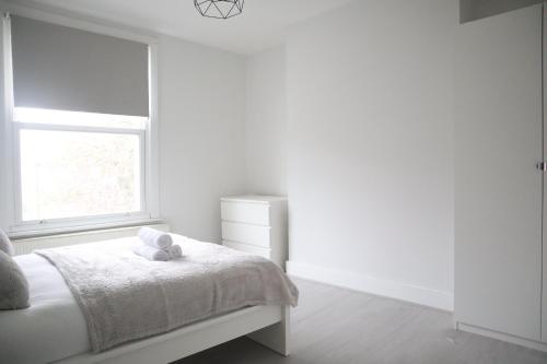 South NorwoodTwelve Thirty Serviced Apartments - 2 Croydon的白色的卧室设有床和窗户