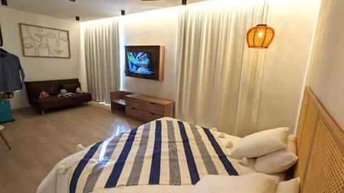 旺德尔港Intense Boutik-Hôtel的一间卧室配有一张床、一台电视和一张沙发