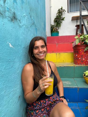 圣路易斯Guarnicê Hostel的坐在墙上拿着饮料的女人