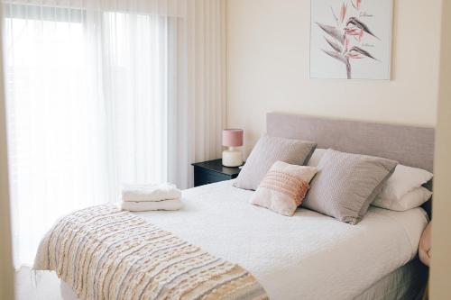 安吉西Exclusive Anglesea River Beach Apartment的一间卧室配有带白色床单和枕头的床。