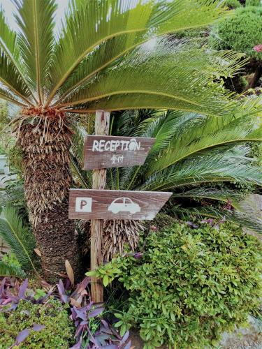 别府快乐尼高酒店的棕榈树和植物度假村的标志