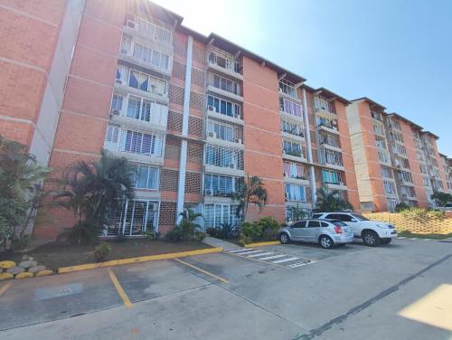 迈克蒂亚Apartamento frente al Aeropuerto de Maiquetía的一座大型公寓楼,两辆车停在停车场