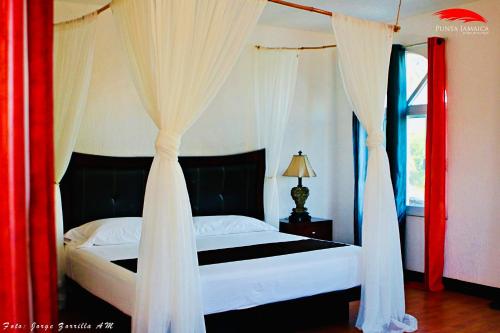 阿卡普尔科Hotel Boutique Punta Jamaica的一间卧室配有带窗帘的床和窗户