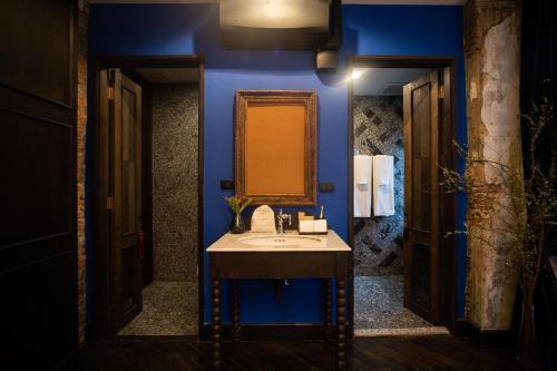 曼谷Baan Tuk Din Hotel的蓝色的浴室设有水槽和镜子