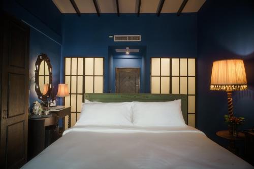曼谷Baan Tuk Din Hotel的卧室配有白色大床和蓝色的墙壁