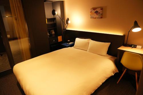 东京东京东神田秋叶原N+酒店的一间酒店客房,配有一张白色的床和一张书桌