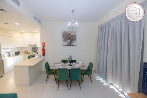 迪拜5 bedroom Villa - Dubai Hills的厨房以及带桌子和绿色椅子的用餐室。