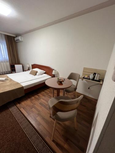 LukavacHOTEL New Milenium的酒店客房带一张床、一张桌子和椅子