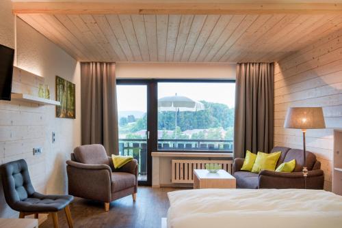 ReichelsheimLandhotel Lortz的酒店客房设有床、椅子和大窗户。
