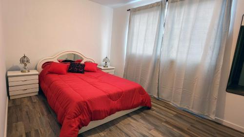 马德普拉塔Departamento con cochera Mar del Plata的一间卧室配有一张带红色毯子的床和窗户。