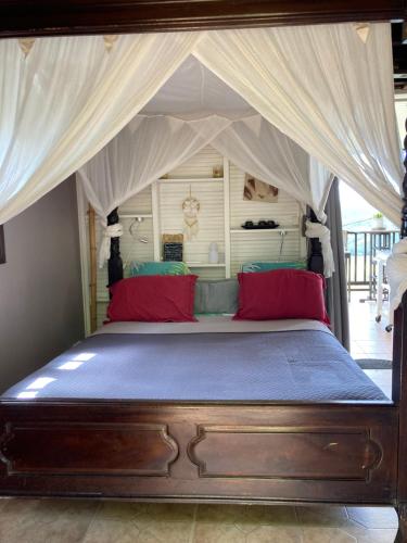 勒马兰Muscade lodge的一间卧室配有一张带红色枕头的天蓬床