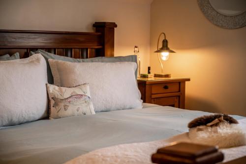 米洛韦格Carters Rest Guesthouse的一张带白色床单和枕头的床以及一盏灯
