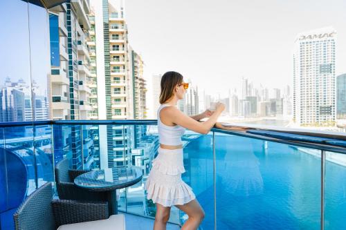 迪拜Hyde Hotel Dubai的站在一个眺望城市的阳台上的女人