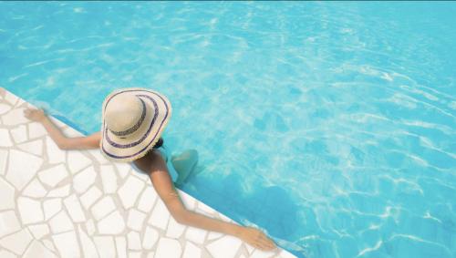 德拉格MiaBella Resort的戴着帽子的女人躺在游泳池里