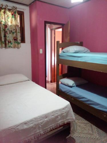 伦索伊斯Suítes Junto e Misturado的紫色墙壁客房内的两张双层床