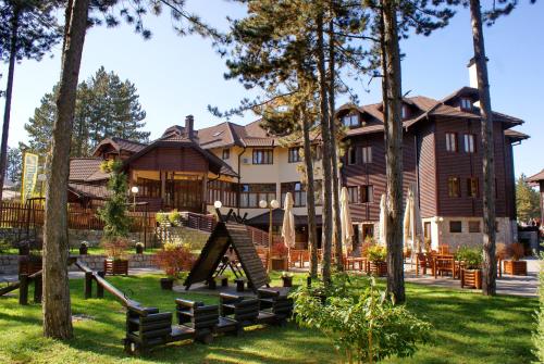 乌日策兹拉蒂波斯卡诺克酒店的一座大房子,有树木和游乐场