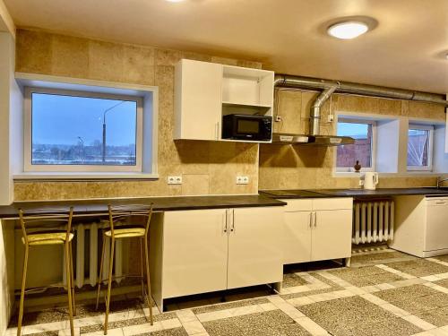 叶尔加瓦Riverside Motel Jelgava的厨房配有白色橱柜和带凳子的台面