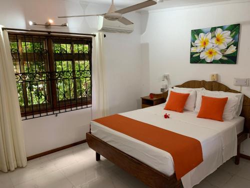 大安塞普拉兰阿米提木屋的一间卧室配有带橙色枕头的床和窗户。