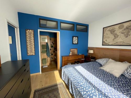 布伦德Une grande terrasse sur la mer的一间卧室设有蓝色的墙壁和一张床