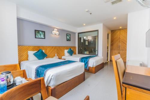 芽庄Venue Hotel Nha Trang的一间卧室配有两张床、一张桌子和一张书桌