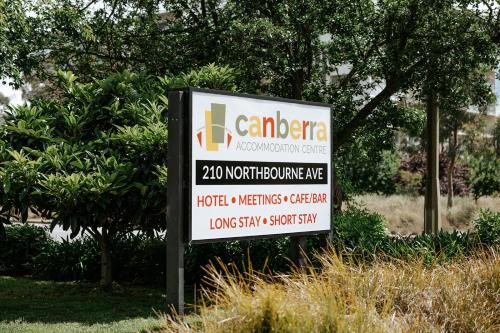 堪培拉Canberra Accommodation Centre的某树前汽车经销商的标志