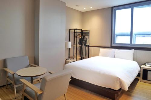 首尔Rosana Hotel的一间卧室配有一张床、一张桌子和一个窗户。