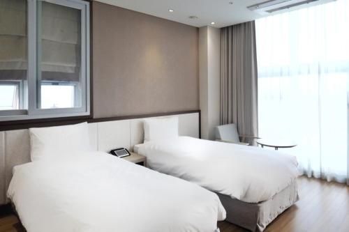 首尔Rosana Hotel的一间酒店客房,设有两张白色的床和窗户。