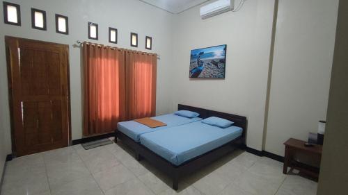 巴芝丹Bintang Homestay Watukarung的一间卧室配有一张带蓝色床单的床和一扇窗户。