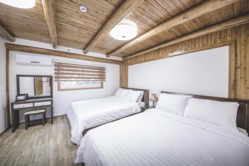 济州市Sunyang Village Dome Caravan的配有木天花板和书桌的客房内的两张床