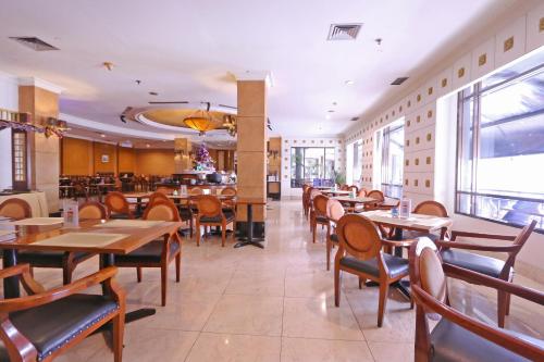 雅加达Hotel Kaisar的一间带木桌椅的餐厅和一间酒吧