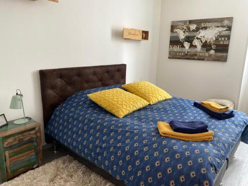 埃佩尔奈Le Loft Vintage Epernay avec Netflix, Vélos, Parking gratuit的一张带蓝色棉被和黄色枕头的床