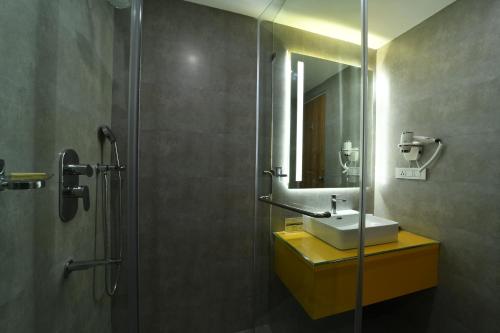 班加罗尔The President Hotel, kumarapark的浴室配有盥洗盆和带镜子的淋浴