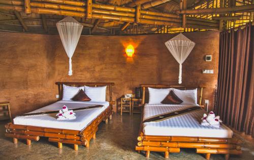 磅湛Hanchey Bamboo Resort的配有两张床的房间的两张床